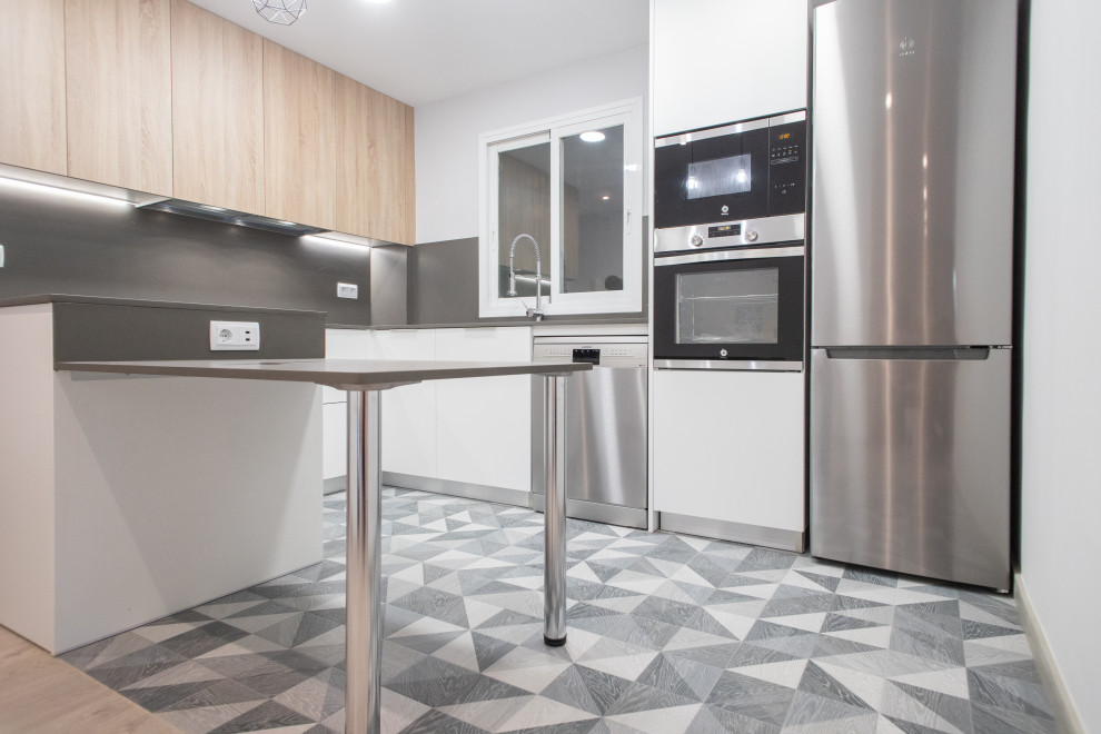 Bild på ett mellanstort funkis grå grått kök, med en dubbel diskho, släta luckor, skåp i mellenmörkt trä, grått stänkskydd, rostfria vitvaror, klinkergolv i keramik och grått golv