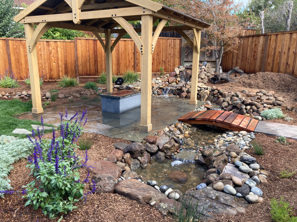 Diseño de jardín de secano retro grande en patio trasero con cascada, piedra decorativa y con madera