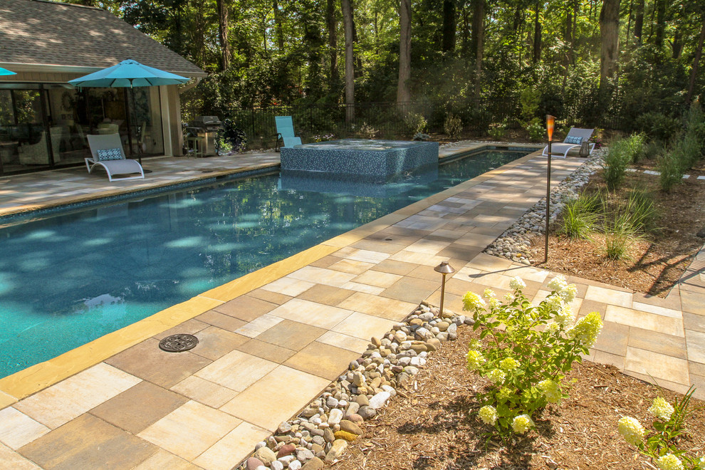 This is an example of a large arts and crafts side yard rectangular lap pool in Other with a pool house and natural stone pavers.