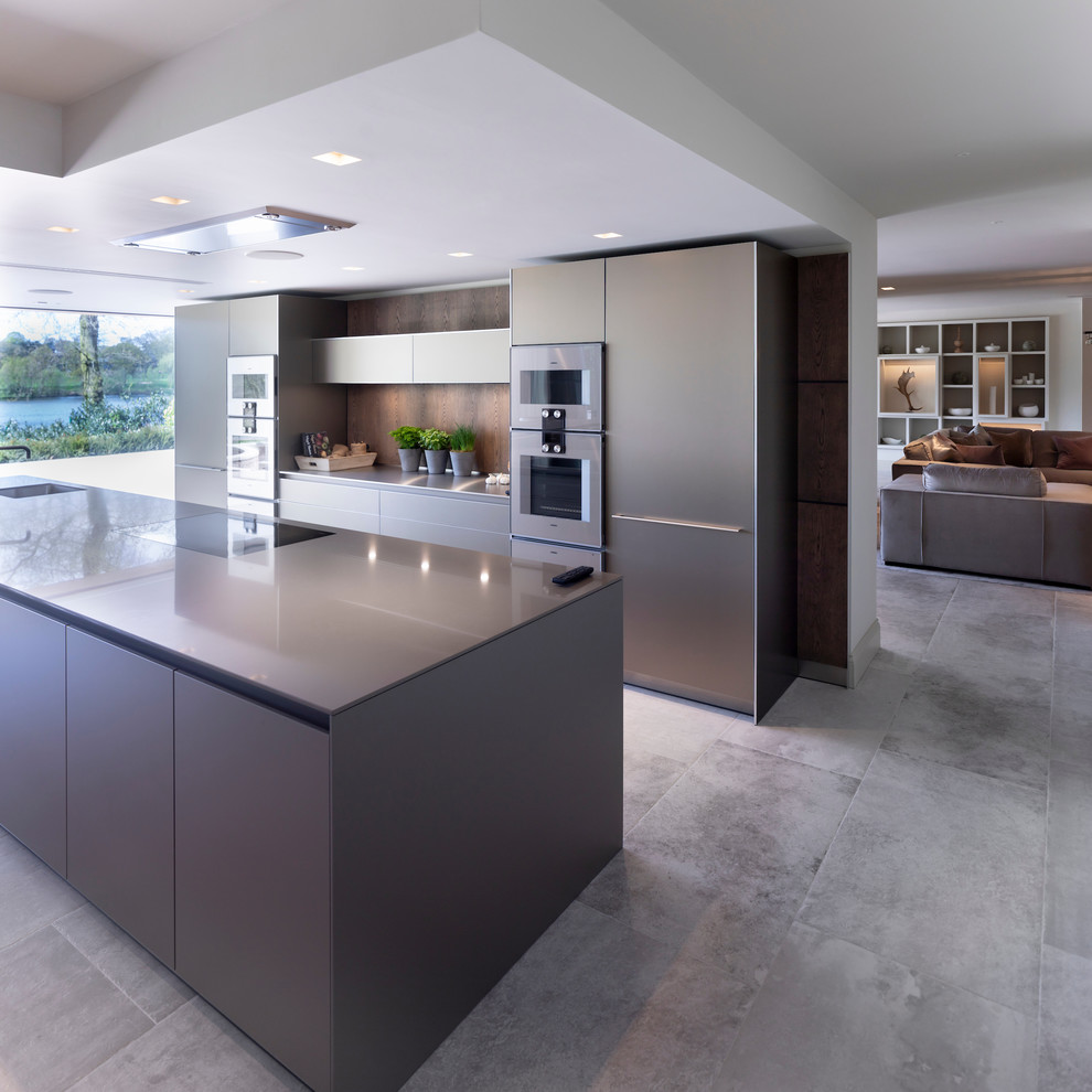 Design ideas for a large contemporary open plan kitchen in Cheshire with an integrated sink, flat-panel cabinets, medium wood cabinets, stainless steel benchtops, timber splashback, stainless steel appliances, ceramic floors, multiple islands, white floor and green benchtop.