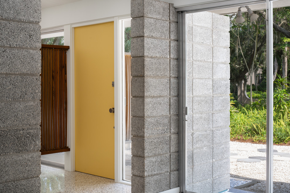 Cette image montre une petite porte d'entrée vintage avec un sol en terrazzo, une porte simple et une porte jaune.