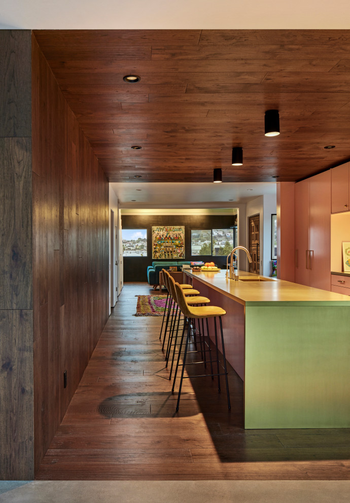 Example of a large tuscan single-wall dark wood floor, wood ceiling and brown floor open concept kitchen design in Los Angeles with an undermount sink, flat-panel cabinets, pink cabinets, yellow backsplash, metal backsplash, stainless steel appliances, an island and yellow countertops