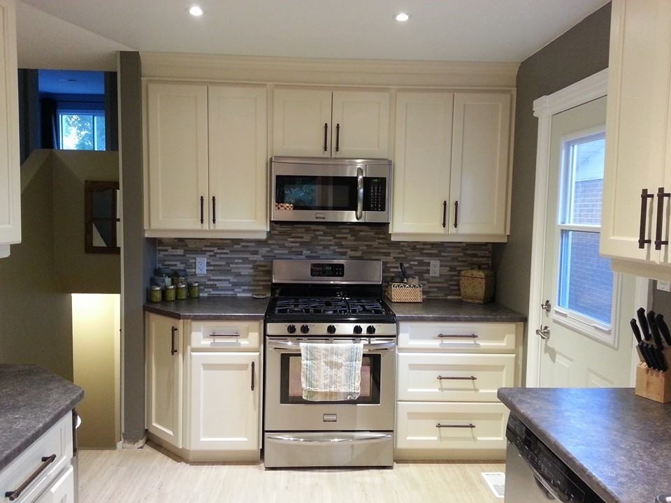Photo of a small arts and crafts galley separate kitchen in Toronto with a double-bowl sink, shaker cabinets, white cabinets, laminate benchtops, multi-coloured splashback, glass sheet splashback, stainless steel appliances, porcelain floors and no island.