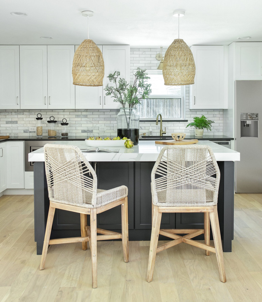 Example of a large beach style u-shaped light wood floor open concept kitchen design in Dallas with an undermount sink, shaker cabinets, white cabinets, quartz countertops, yellow backsplash, marble backsplash, stainless steel appliances, an island and white countertops