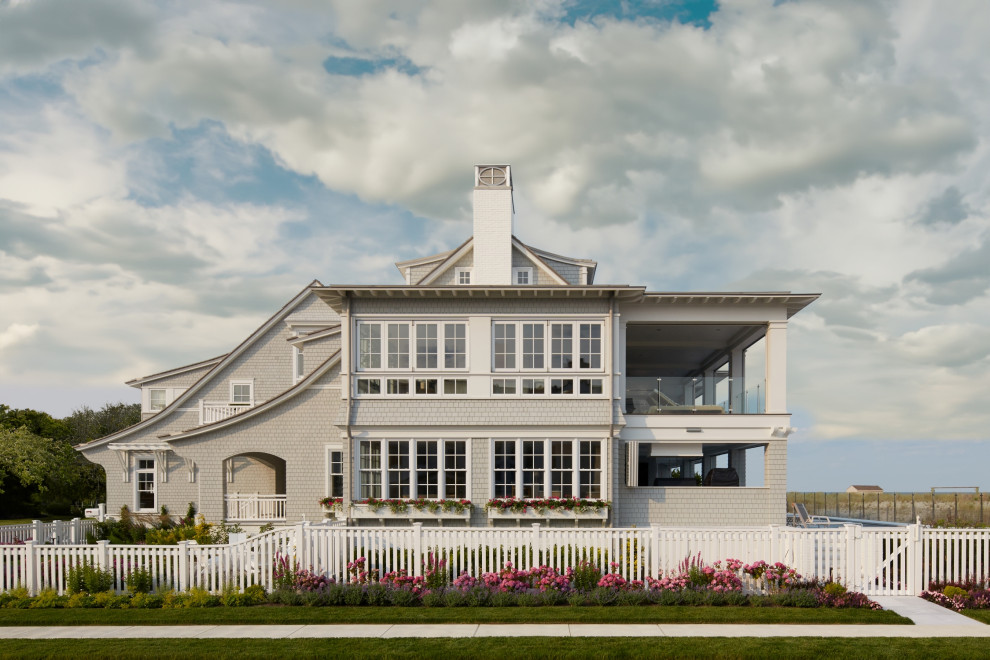 На фото: двухэтажный, серый частный загородный дом в морском стиле с двускатной крышей, крышей из гибкой черепицы, коричневой крышей и отделкой дранкой с