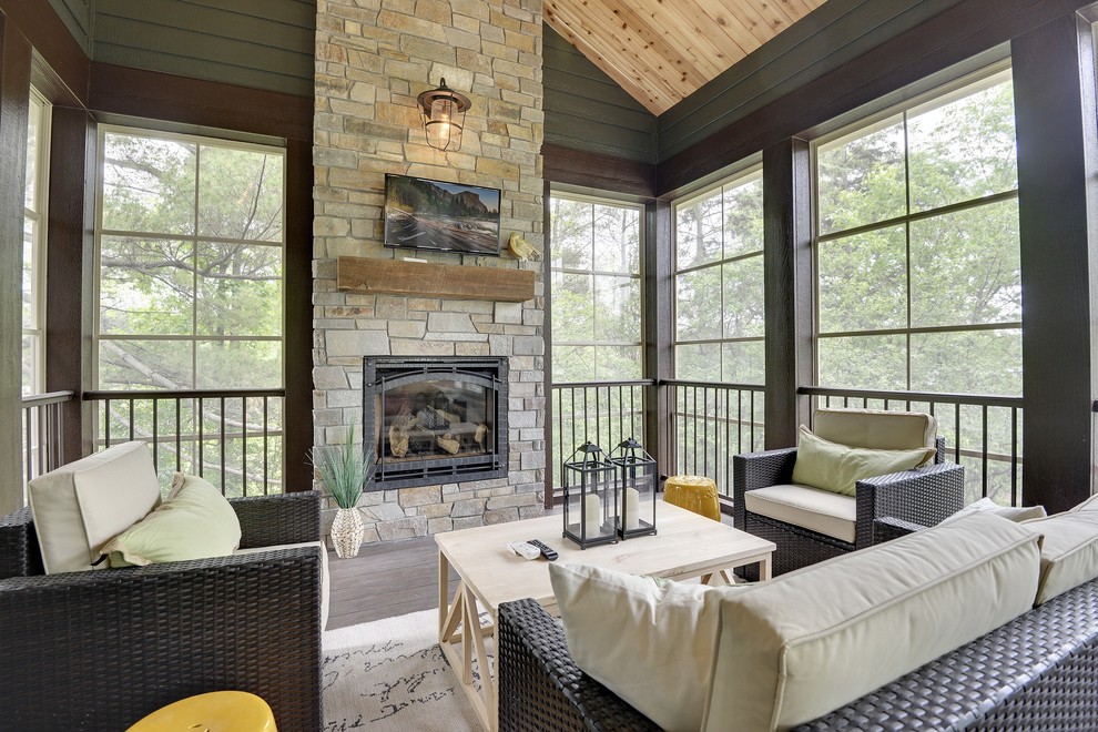 Transitional sunroom in Minneapolis with a standard fireplace, a stone fireplace surround and grey floor.