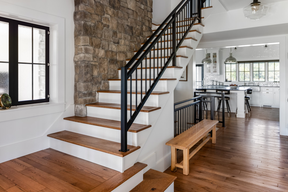 Large country wood u-shaped staircase in Columbus with painted wood risers and metal railing.