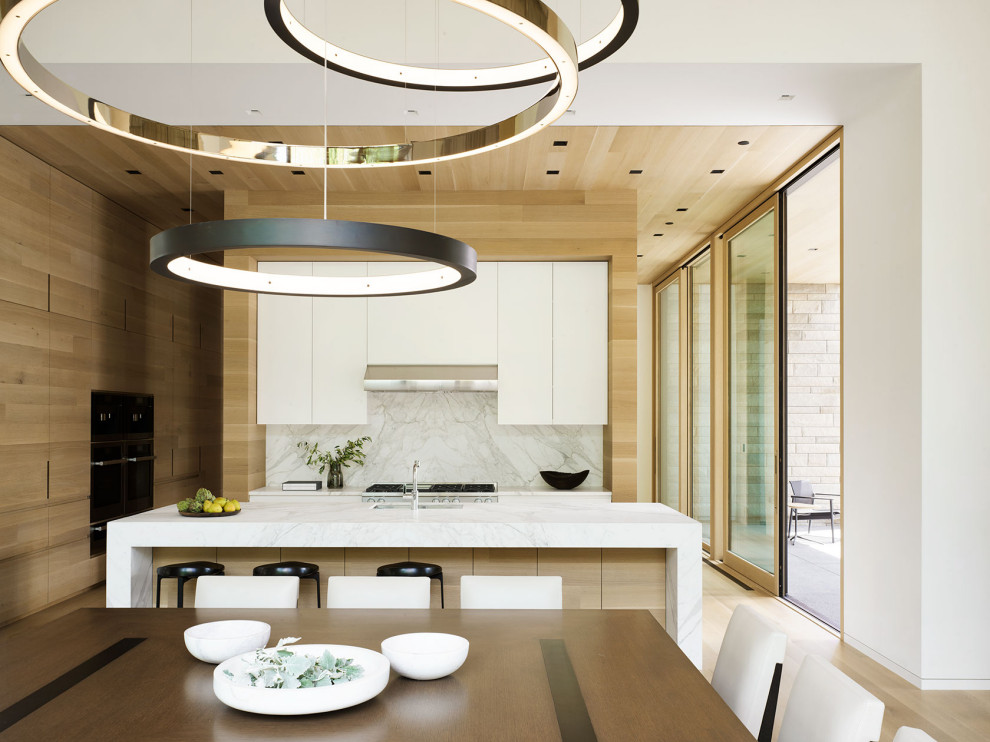 Cette image montre une cuisine américaine minimaliste avec un placard à porte plane, des portes de placard blanches, parquet clair, îlot, un plan de travail blanc et un plafond en bois.