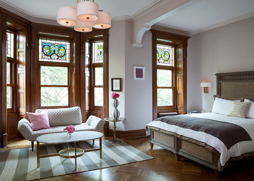 Inspiration for an eclectic master bedroom in New York with medium hardwood floors and a standard fireplace.