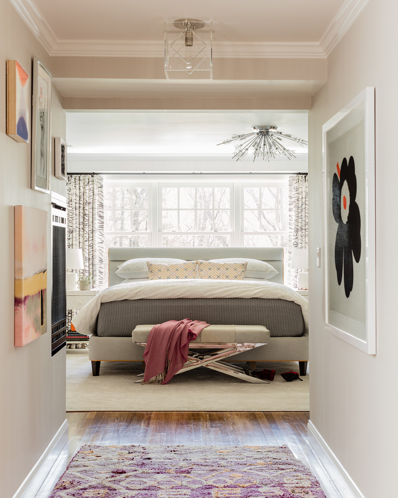 Inspiration for a large transitional master bedroom in Boston with grey walls, medium hardwood floors, a two-sided fireplace, a plaster fireplace surround and brown floor.