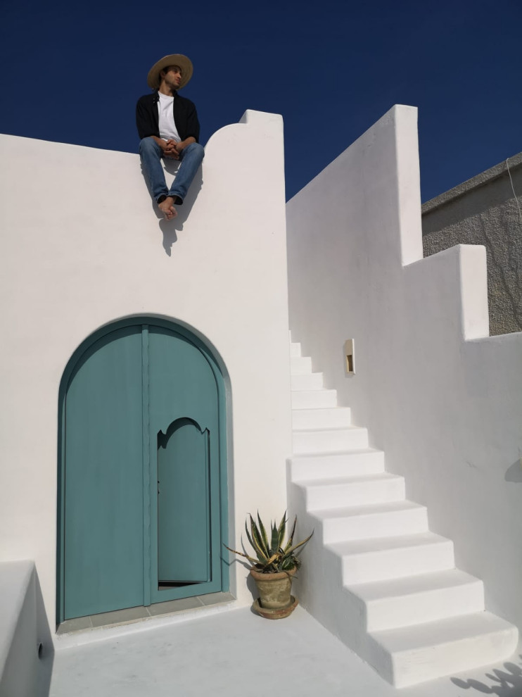 Cette image montre une grande façade de maison blanche méditerranéenne en stuc à un étage avec un toit plat et un toit blanc.