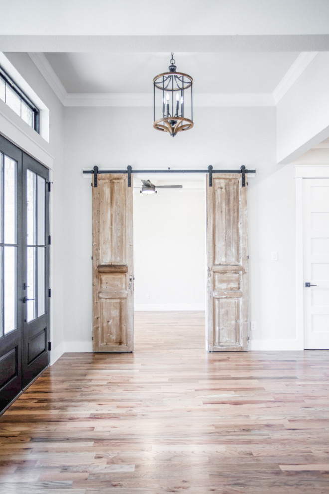 Inspiration for a large country foyer in Dallas with white walls, medium hardwood floors, a double front door, a glass front door and brown floor.