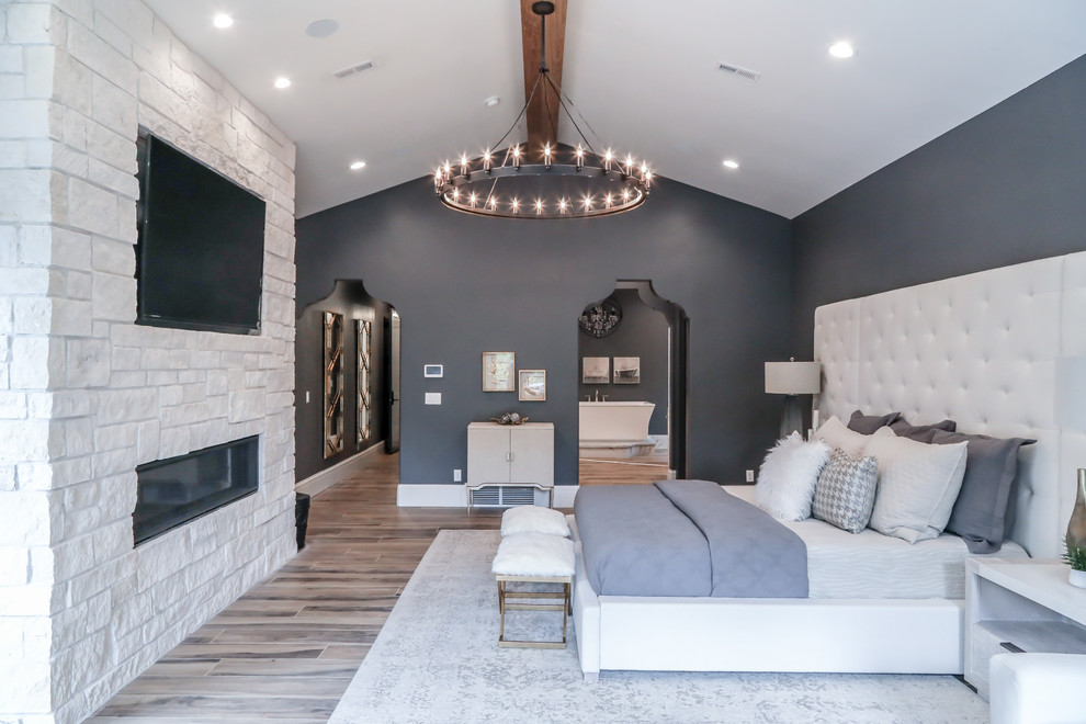Design ideas for a large mediterranean master bedroom in Salt Lake City with grey walls, porcelain floors, a stone fireplace surround, brown floor and a ribbon fireplace.