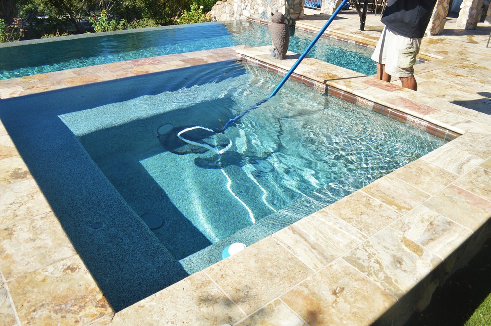 Exemple d'une piscine arrière chic de taille moyenne et sur mesure avec un point d'eau et des pavés en pierre naturelle.
