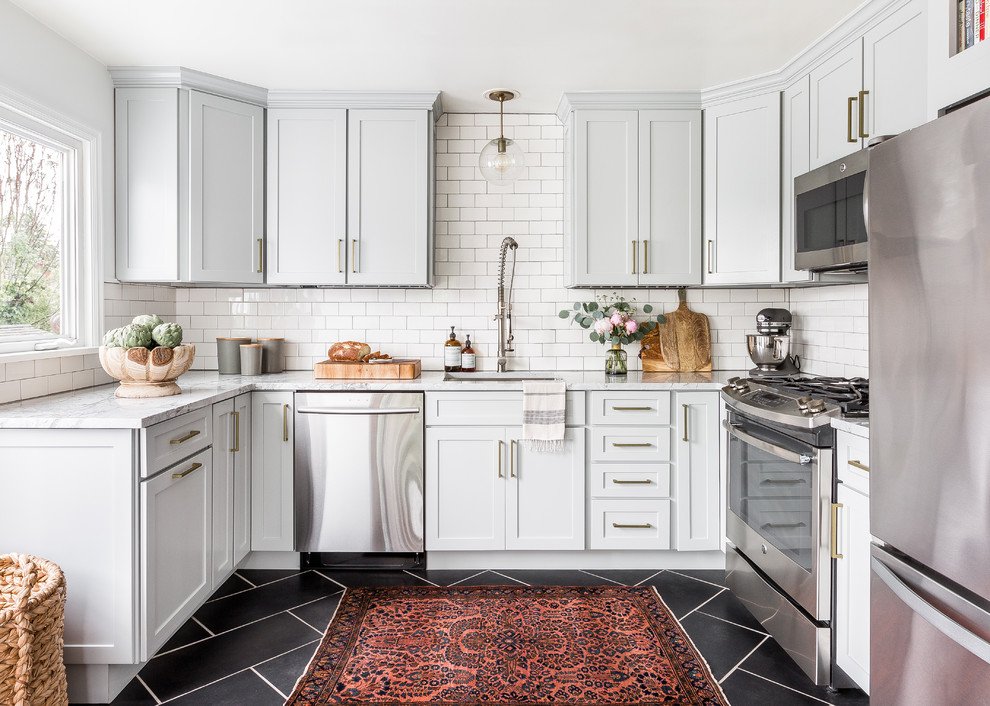 Transitional u-shaped kitchen in Seattle with an undermount sink, shaker cabinets, grey cabinets, white splashback, subway tile splashback, stainless steel appliances, no island and black floor.