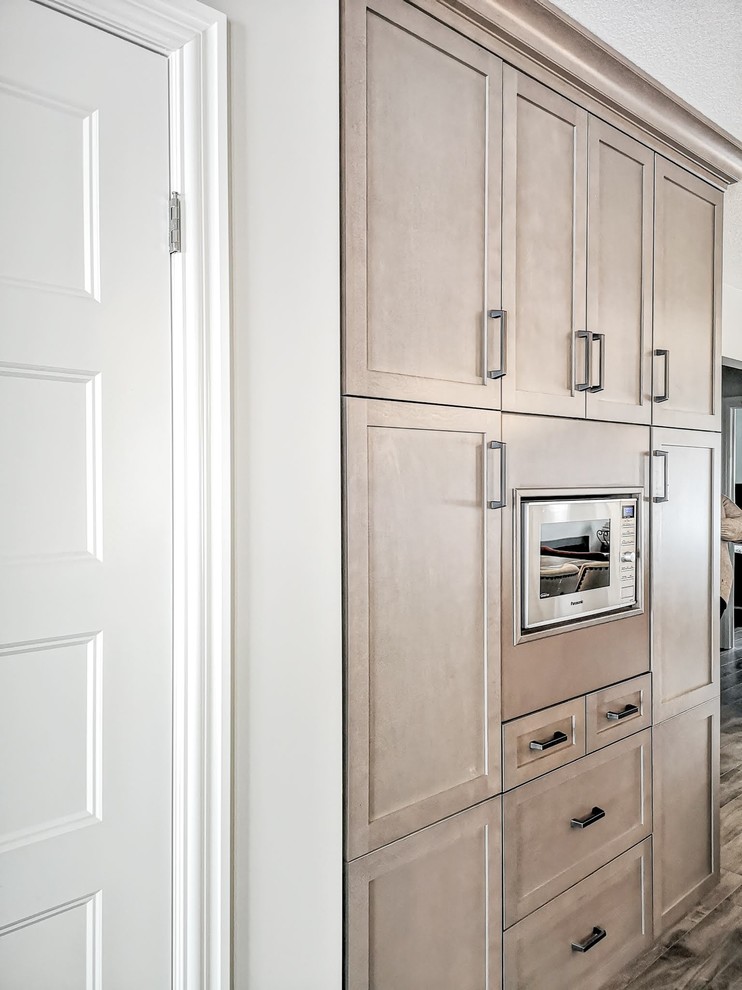 Mid-sized transitional l-shaped medium tone wood floor and brown floor open concept kitchen photo in Toronto with an undermount sink, shaker cabinets, light wood cabinets, granite countertops, white backsplash, porcelain backsplash, stainless steel appliances, an island and beige countertops