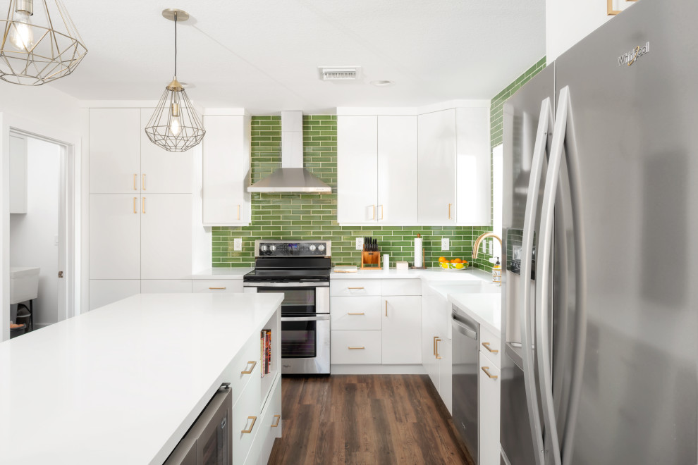 Mid-sized midcentury l-shaped open plan kitchen in Phoenix with a farmhouse sink, flat-panel cabinets, white cabinets, quartz benchtops, green splashback, ceramic splashback, stainless steel appliances, vinyl floors, with island, brown floor and white benchtop.