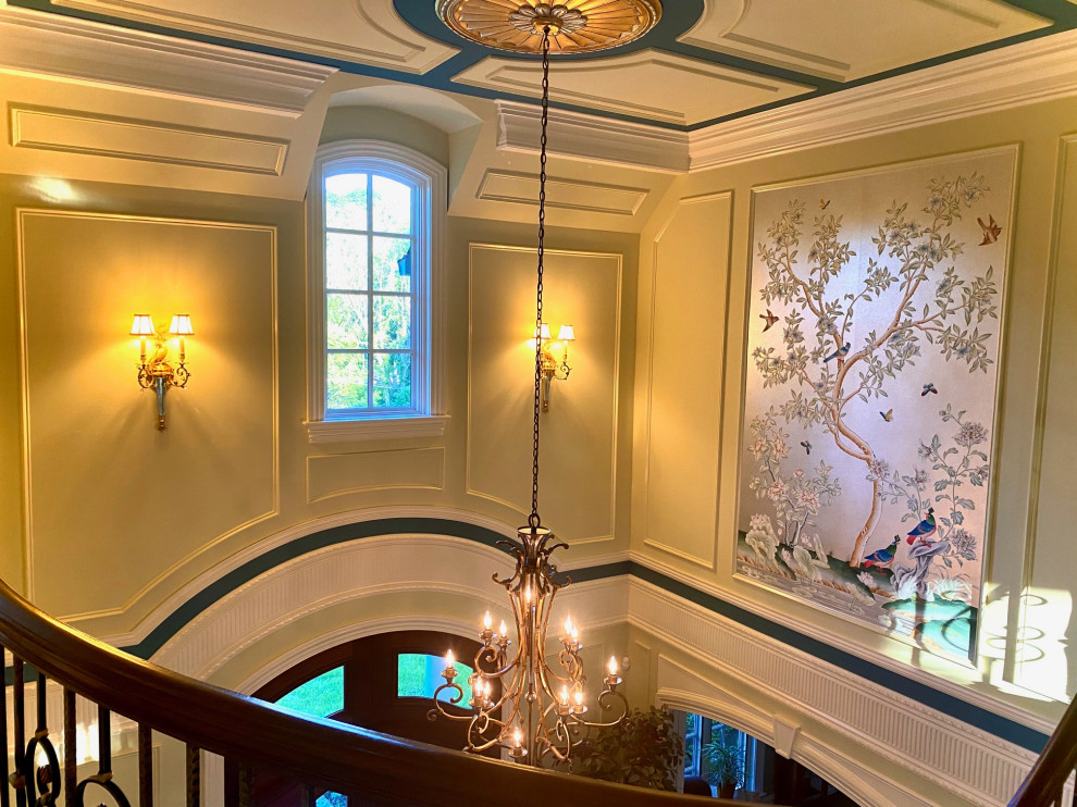 Пример оригинального дизайна: большое фойе в классическом стиле с зелеными стенами, мраморным полом, двустворчатой входной дверью, коричневой входной дверью, белым полом, кессонным потолком и панелями на части стены