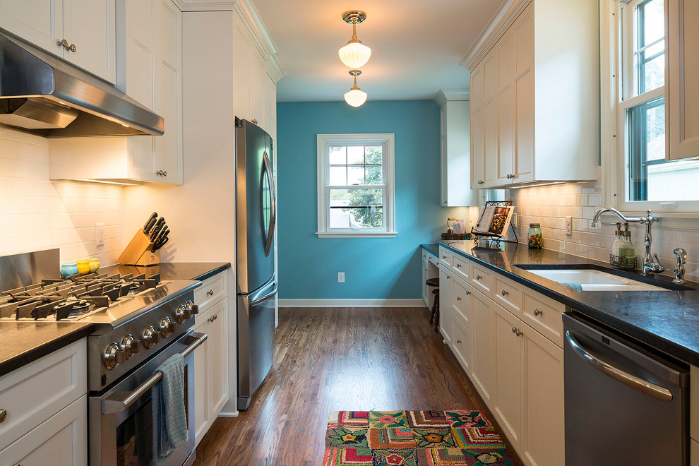 This is an example of a traditional galley separate kitchen in Minneapolis with an undermount sink, recessed-panel cabinets, white cabinets, white splashback, subway tile splashback and stainless steel appliances.