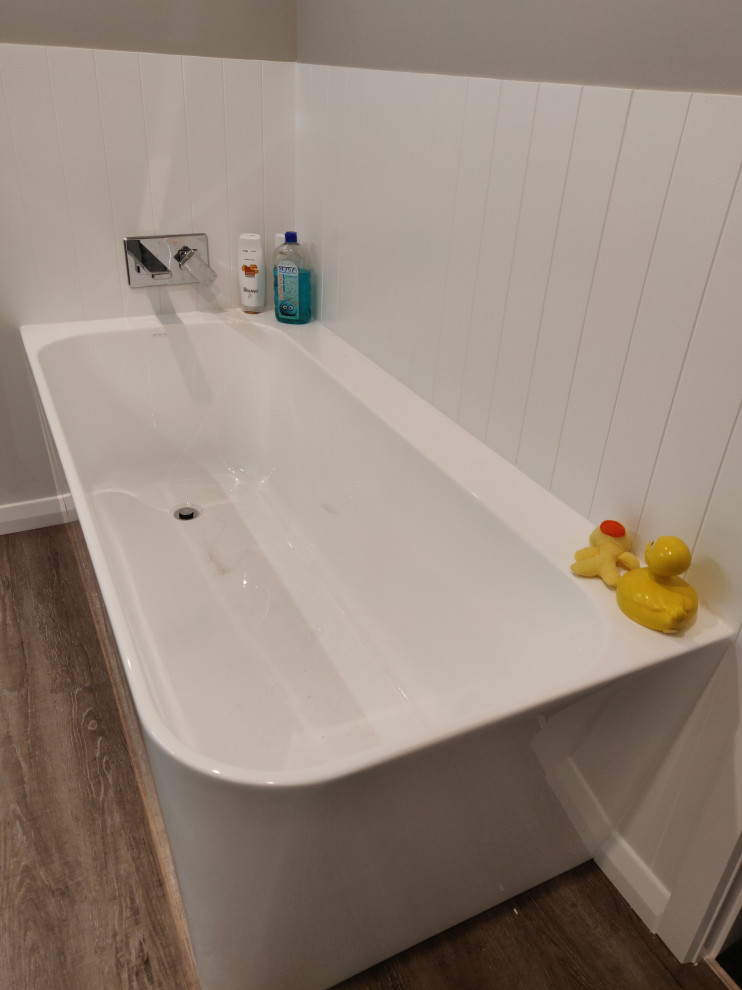 Photo of a small contemporary bathroom in Hamilton with a corner tub, a corner shower, grey walls, laminate floors, grey floor and a hinged shower door.
