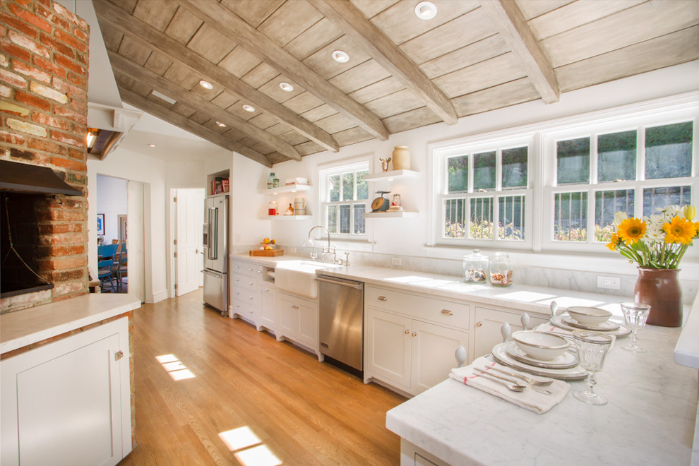 This is an example of a traditional separate kitchen in Los Angeles with marble benchtops, stainless steel appliances, a farmhouse sink, shaker cabinets and white cabinets.