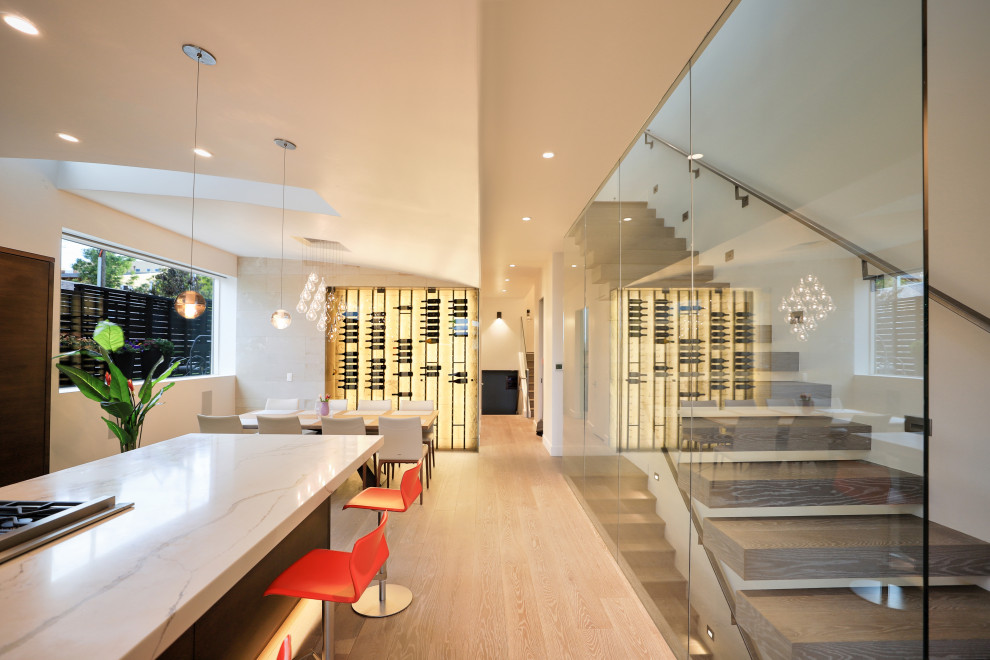 Стильный дизайн: большая кухня-столовая в стиле модернизм с белыми стенами, паркетным полом среднего тона, горизонтальным камином, фасадом камина из камня и коричневым полом - последний тренд