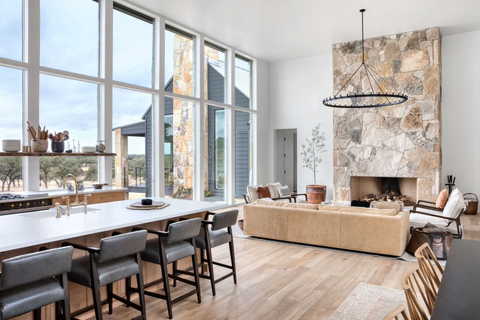 Offenes Landhausstil Wohnzimmer mit weißer Wandfarbe, hellem Holzboden, Kamin und Kaminumrandung aus Stein in Austin
