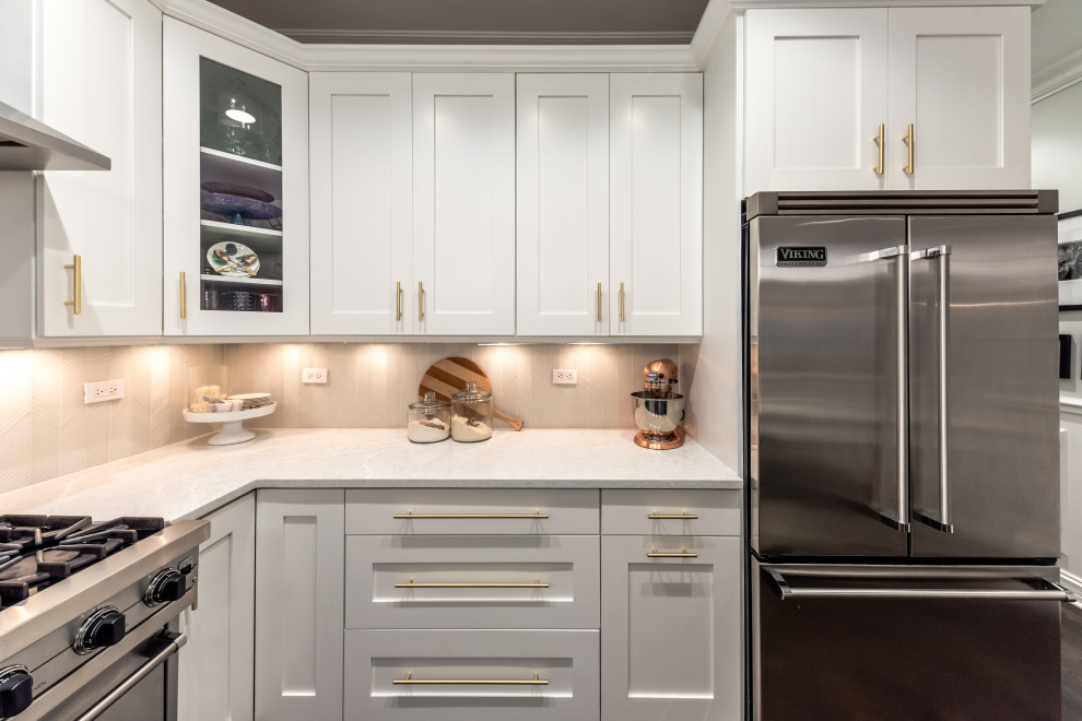 Eat-in kitchen - mid-sized transitional u-shaped dark wood floor and brown floor eat-in kitchen idea in Chicago with a farmhouse sink, shaker cabinets, white cabinets, quartz countertops, gray backsplash, glass tile backsplash, stainless steel appliances, a peninsula and gray countertops