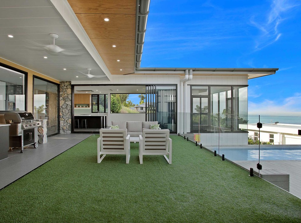 Contemporary backyard deck in Other with a roof extension.