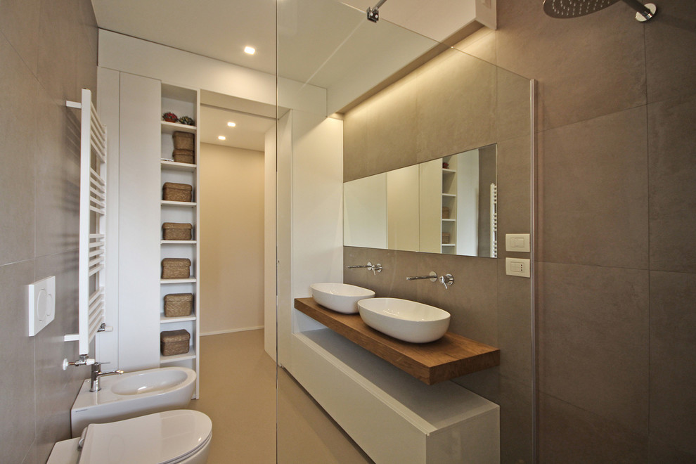 Large scandinavian 3/4 bathroom in Milan with flat-panel cabinets, white cabinets, a curbless shower, a two-piece toilet, beige tile, porcelain tile, beige walls, concrete floors, a vessel sink, wood benchtops, beige floor and an open shower.