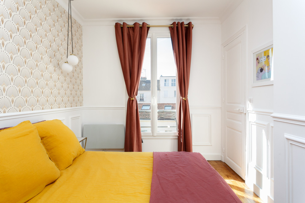 Ejemplo de dormitorio principal de tamaño medio sin chimenea con paredes blancas, suelo de madera en tonos medios, suelo marrón y papel pintado