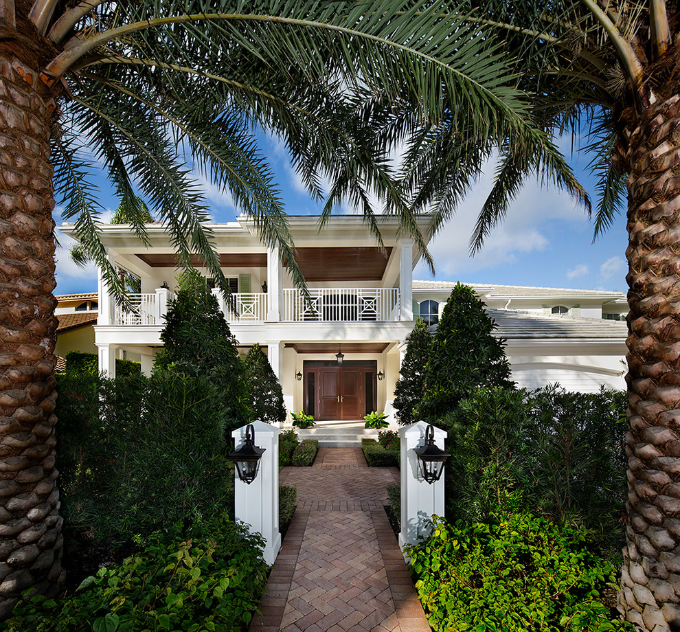 This is an example of a large traditional front door in Miami with a double front door, a dark wood front door, white walls, brick floors and brown floor.