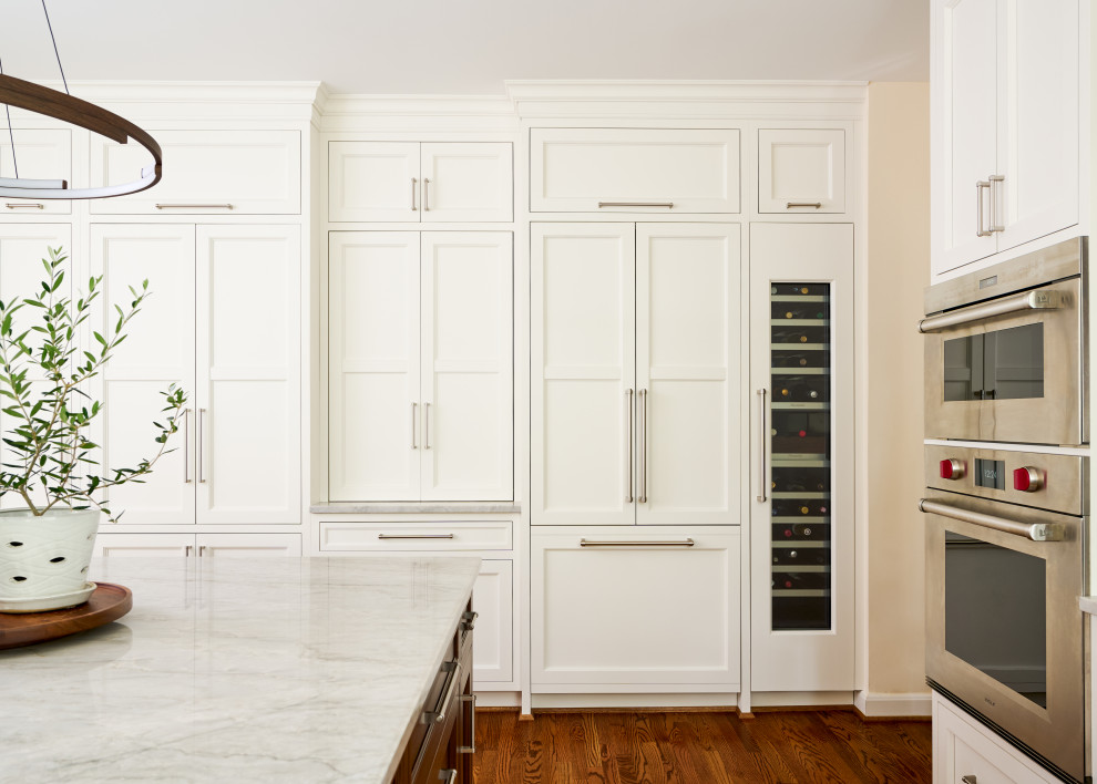 Example of a mid-sized transitional u-shaped medium tone wood floor and brown floor open concept kitchen design in DC Metro with an undermount sink, recessed-panel cabinets, white cabinets, marble countertops, multicolored backsplash, marble backsplash, paneled appliances, an island and multicolored countertops