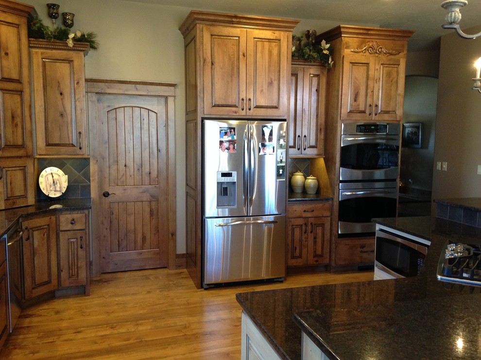 Eat-in kitchen - mid-sized rustic single-wall medium tone wood floor and brown floor eat-in kitchen idea with raised-panel cabinets, light wood cabinets, granite countertops, stainless steel appliances and an island