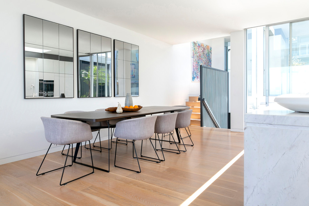 Large contemporary open plan dining in Sydney with white walls, medium hardwood floors and beige floor.