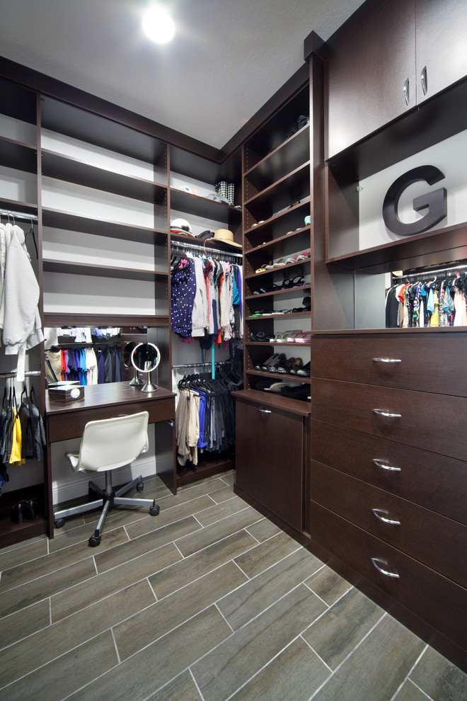 Mid-sized transitional gender-neutral walk-in wardrobe in Orlando with flat-panel cabinets, dark wood cabinets and porcelain floors.