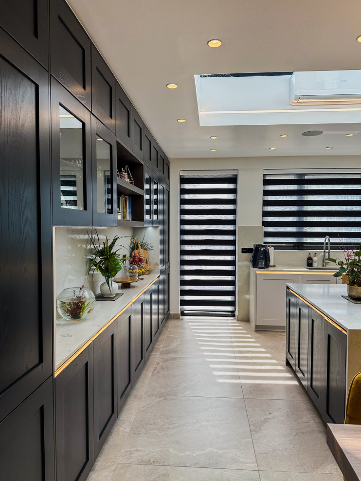 Design ideas for a large traditional l-shaped kitchen/diner in London with a built-in sink, shaker cabinets, blue cabinets, quartz worktops, white splashback, engineered quartz splashback, integrated appliances, porcelain flooring, an island, beige floors, white worktops and feature lighting.