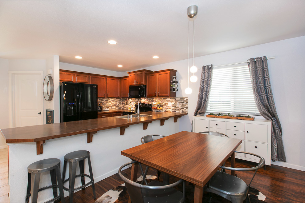 Mid-sized transitional u-shaped medium tone wood floor open concept kitchen photo in Seattle with a drop-in sink, shaker cabinets, medium tone wood cabinets, wood countertops, multicolored backsplash, matchstick tile backsplash, black appliances and a peninsula