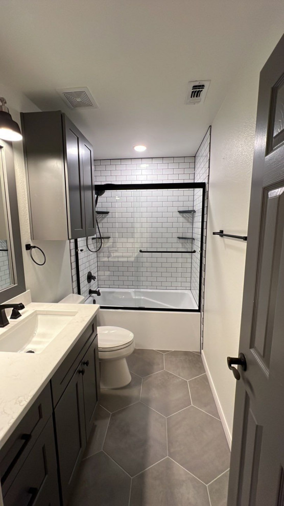 Exemple d'une salle de bain nature avec des portes de placard grises, une baignoire posée, un combiné douche/baignoire, un sol en carrelage de porcelaine, un lavabo encastré, un plan de toilette en quartz modifié, un sol gris, une cabine de douche à porte coulissante, un plan de toilette blanc et meuble simple vasque.