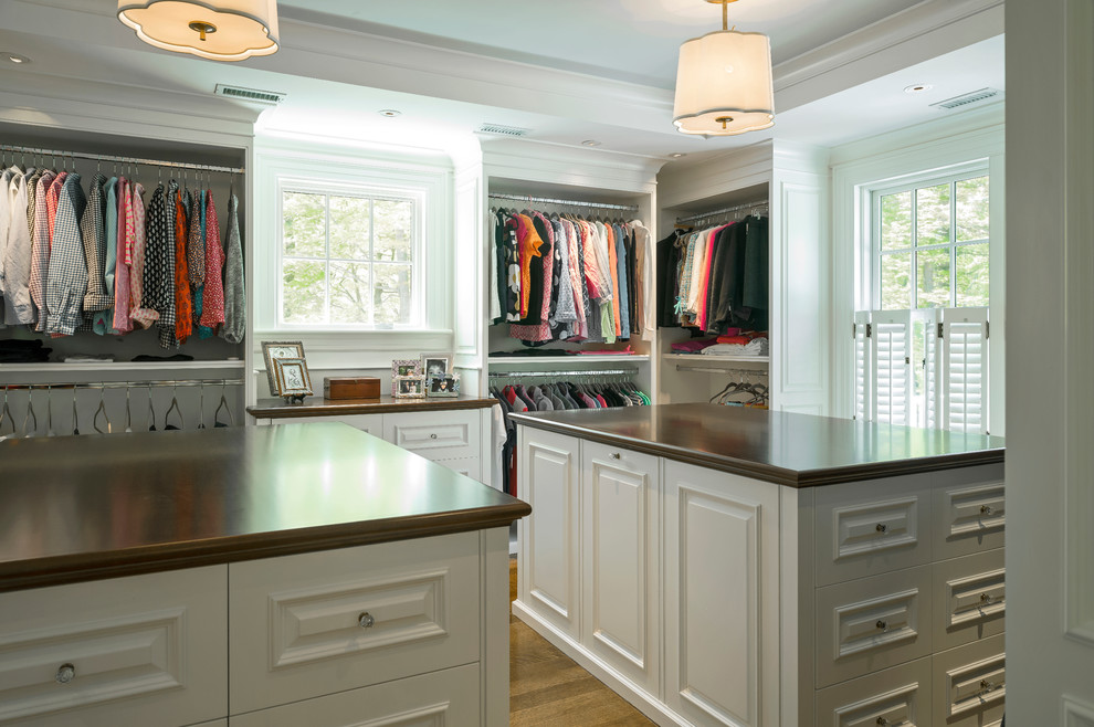 Photo of an expansive traditional gender-neutral walk-in wardrobe in Boston with white cabinets, medium hardwood floors and raised-panel cabinets.