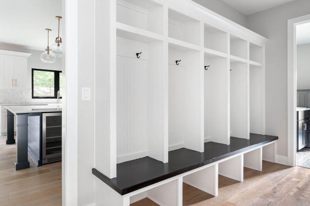 This is an example of a large country mudroom in Chicago with grey walls, light hardwood floors and beige floor.