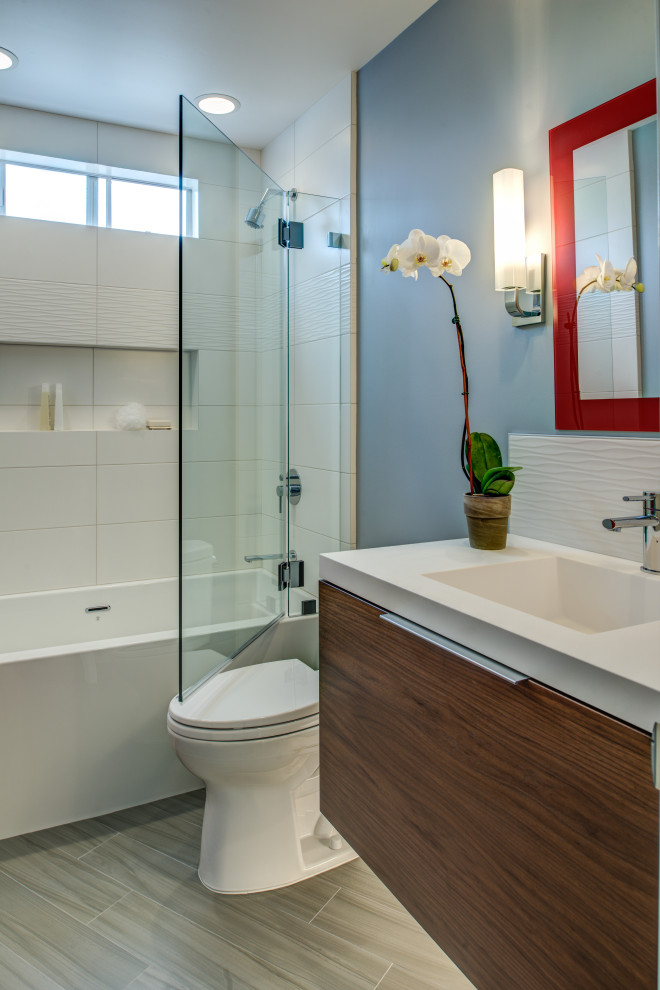 Photo of a medium sized world-inspired bathroom in San Francisco with flat-panel cabinets, brown cabinets, an alcove bath, a shower/bath combination, a two-piece toilet, white tiles, ceramic tiles, blue walls, porcelain flooring, an integrated sink, solid surface worktops, grey floors, an open shower, white worktops, a wall niche, a single sink and a floating vanity unit.