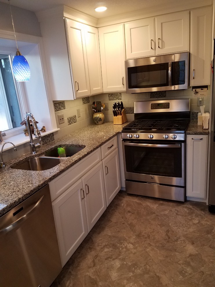 Inspiration for a mid-sized transitional brown floor and ceramic tile eat-in kitchen remodel in Boston with a double-bowl sink, shaker cabinets, white cabinets, granite countertops, white backsplash, ceramic backsplash, stainless steel appliances and a peninsula