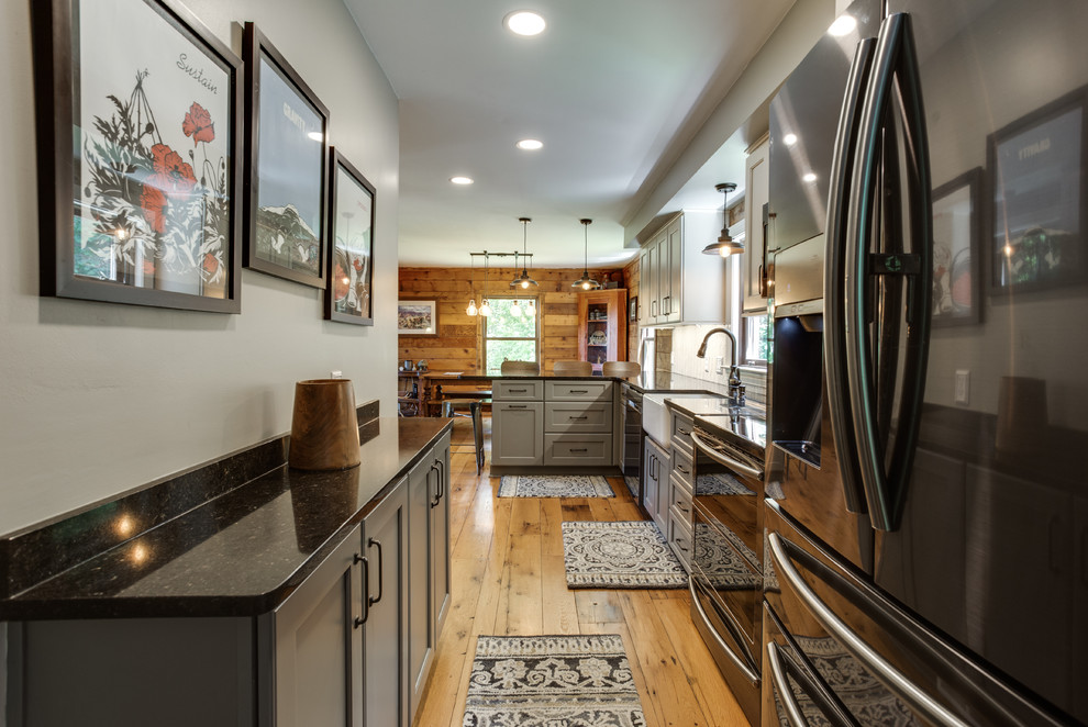 This is an example of a traditional l-shaped kitchen in DC Metro with a farmhouse sink, recessed-panel cabinets, stainless steel appliances, medium hardwood floors and a peninsula.