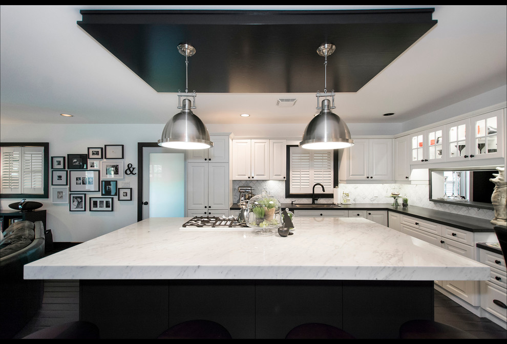 Inspiration for a mid-sized transitional l-shaped black floor open concept kitchen remodel with an undermount sink, raised-panel cabinets, white cabinets, marble countertops, white backsplash, marble backsplash, stainless steel appliances and an island