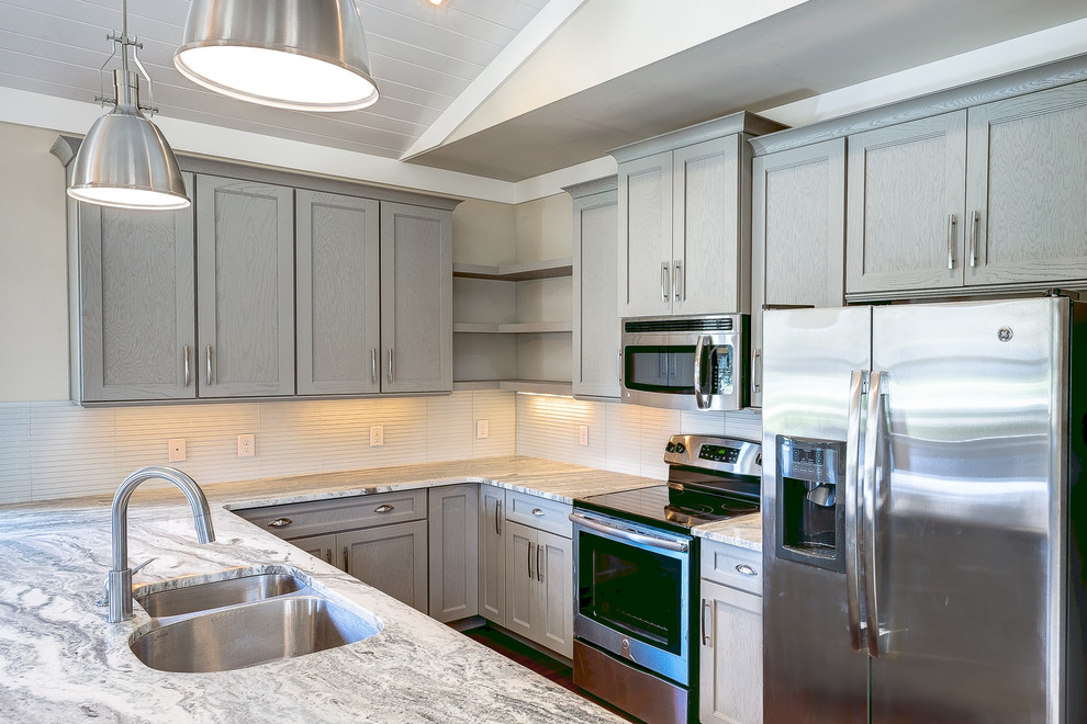 Photo of a mid-sized contemporary u-shaped kitchen in Miami with a peninsula, a double-bowl sink, beaded inset cabinets, grey cabinets, granite benchtops, white splashback, stainless steel appliances and laminate floors.
