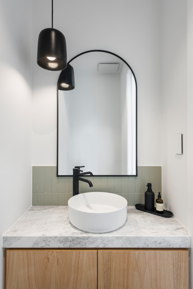 This is an example of a small contemporary cloakroom in Adelaide with open cabinets, light wood cabinets, a wall mounted toilet, green tiles, ceramic tiles, white walls, cement flooring, a vessel sink, marble worktops, black floors, grey worktops, a floating vanity unit and wood walls.