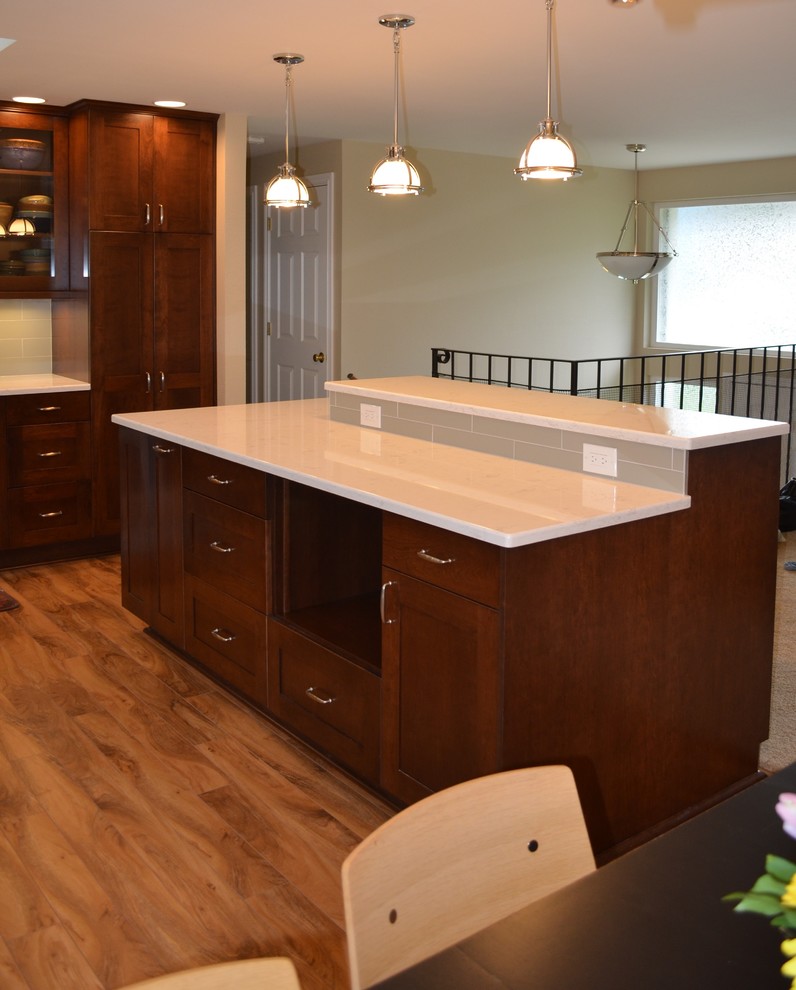 Open concept kitchen - mid-sized transitional l-shaped medium tone wood floor and brown floor open concept kitchen idea in Seattle with an undermount sink, shaker cabinets, dark wood cabinets, quartz countertops, stainless steel appliances, an island, gray backsplash and subway tile backsplash