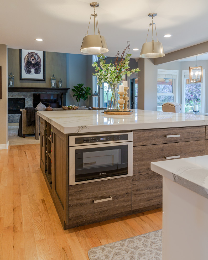 Inspiration for a mid-sized country eat-in kitchen in Denver with an undermount sink, shaker cabinets, white cabinets, quartzite benchtops, grey splashback, ceramic splashback, stainless steel appliances, medium hardwood floors, with island and white benchtop.