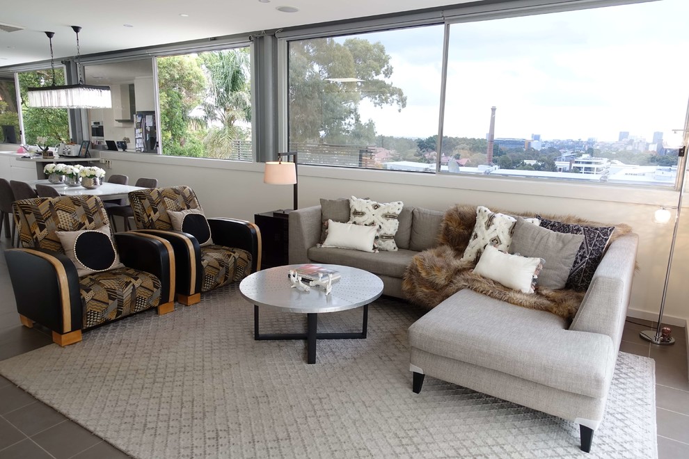 Photo of a large transitional open concept living room in Sydney with white walls, ceramic floors, a freestanding tv and grey floor.